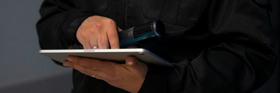 Sicherheitskraft mit Tablet und Taschenlampe bei Analyse – individuelle Sicherheitsberatung durch Krüger Security in Berlin